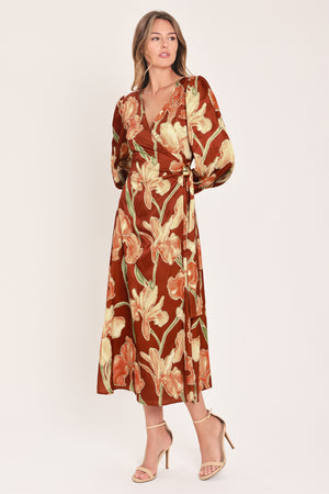 A woman modeling a long-sleeve midi wrap dress with a brown, beige, and green floral pattern | Flying Tomato