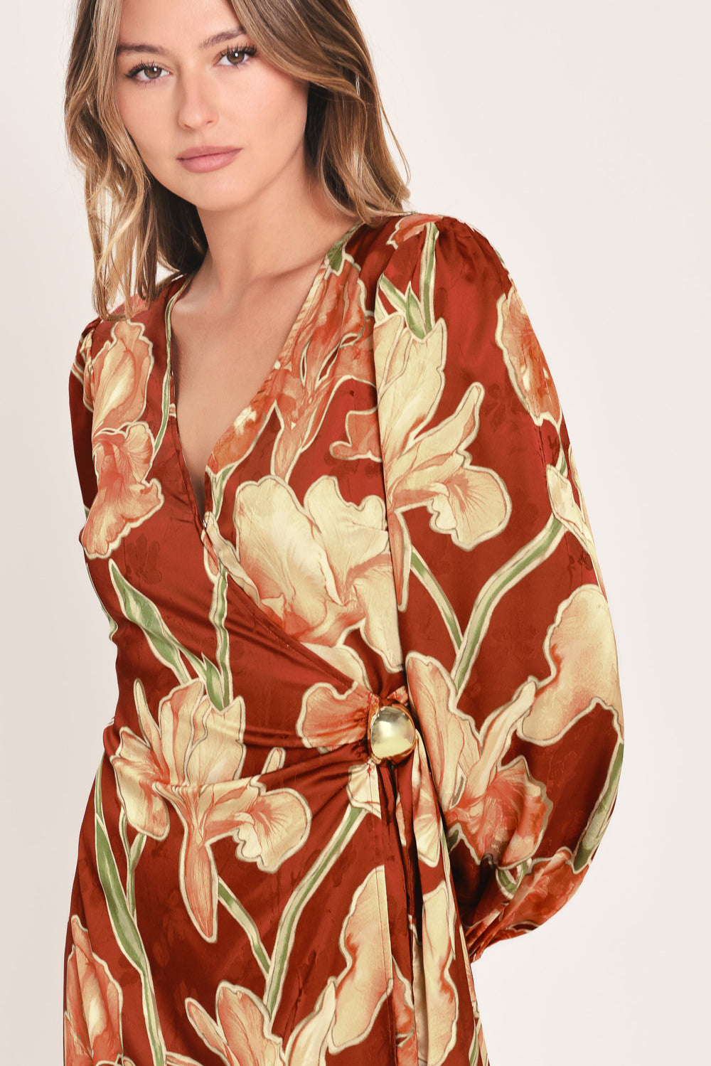 A woman modeling a long-sleeve midi wrap dress with a brown, beige, and green floral pattern | Flying Tomato