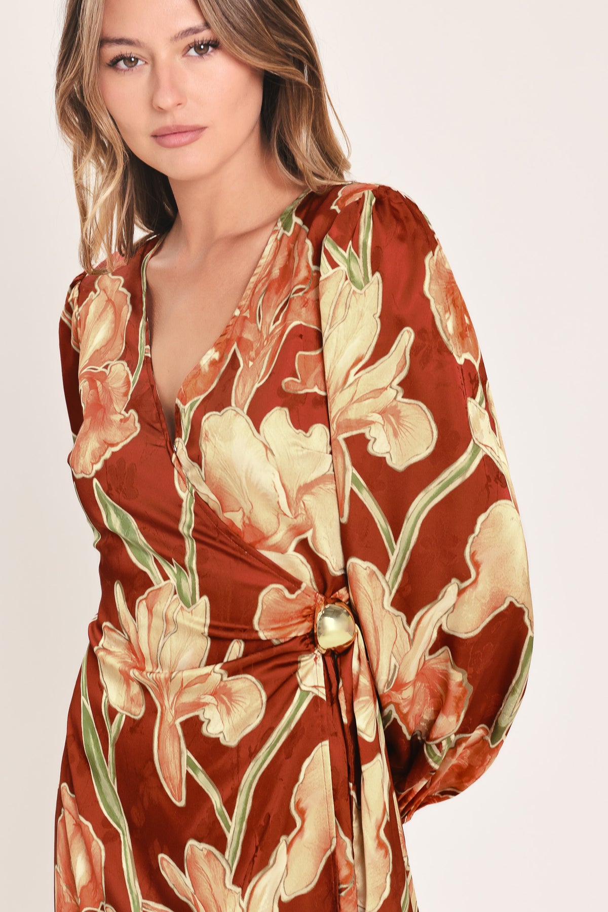 A woman modeling a long-sleeve midi wrap dress with a brown, beige, and green floral pattern | Flying Tomato