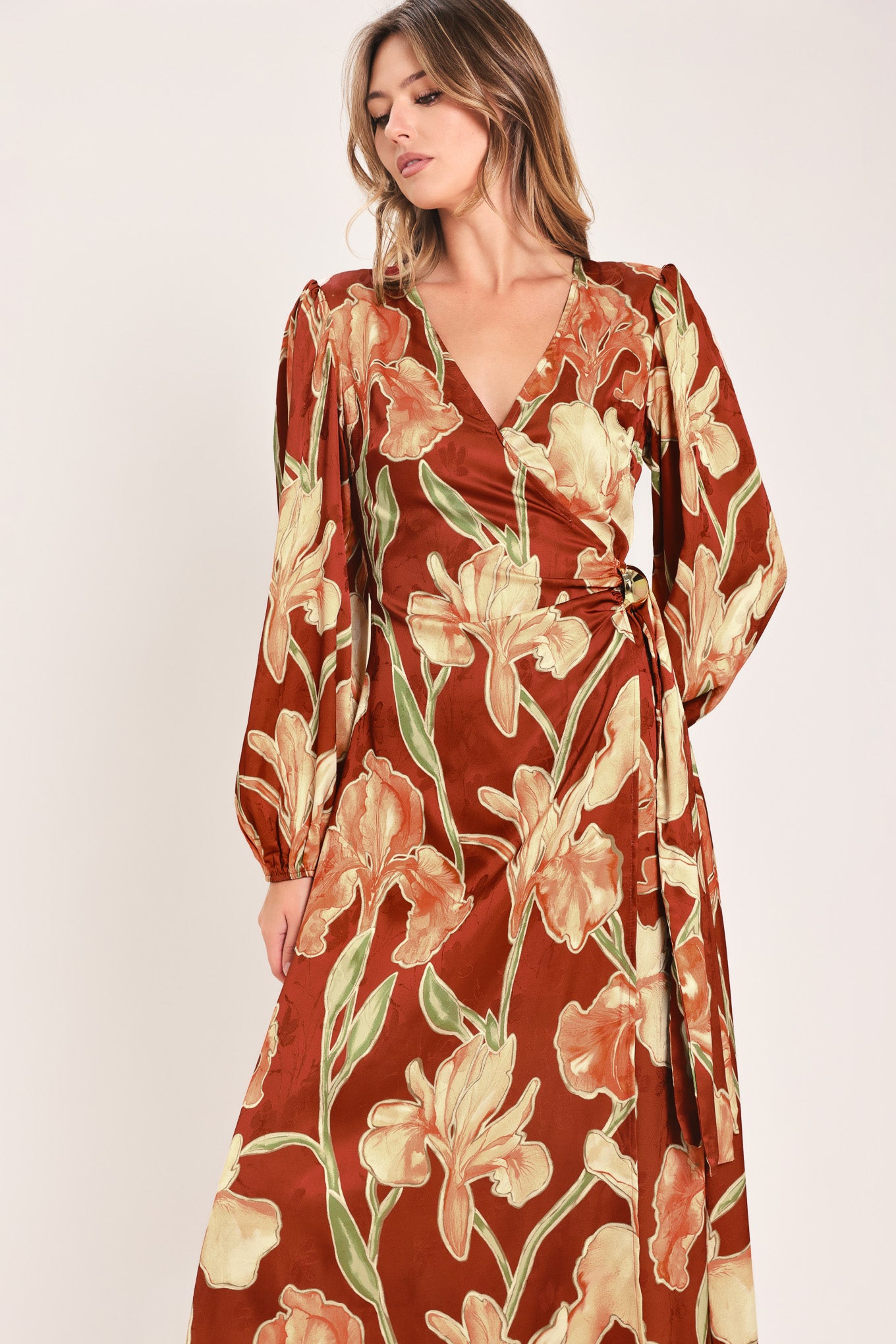 A woman modeling a long-sleeve midi wrap dress with a brown, beige, and green floral pattern | Flying Tomato