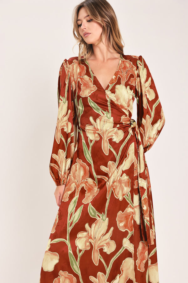A woman modeling a long-sleeve midi wrap dress with a brown, beige, and green floral pattern | Flying Tomato