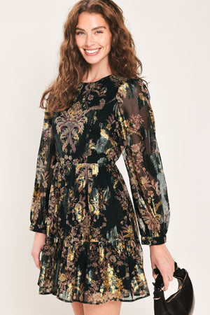 Woman wearing a black long sleeve mini dress with metallic baroque print and tiered skirt | Flying Tomato