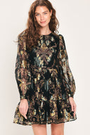 Woman wearing a black long sleeve mini dress with metallic baroque print and tiered skirt | Flying Tomato