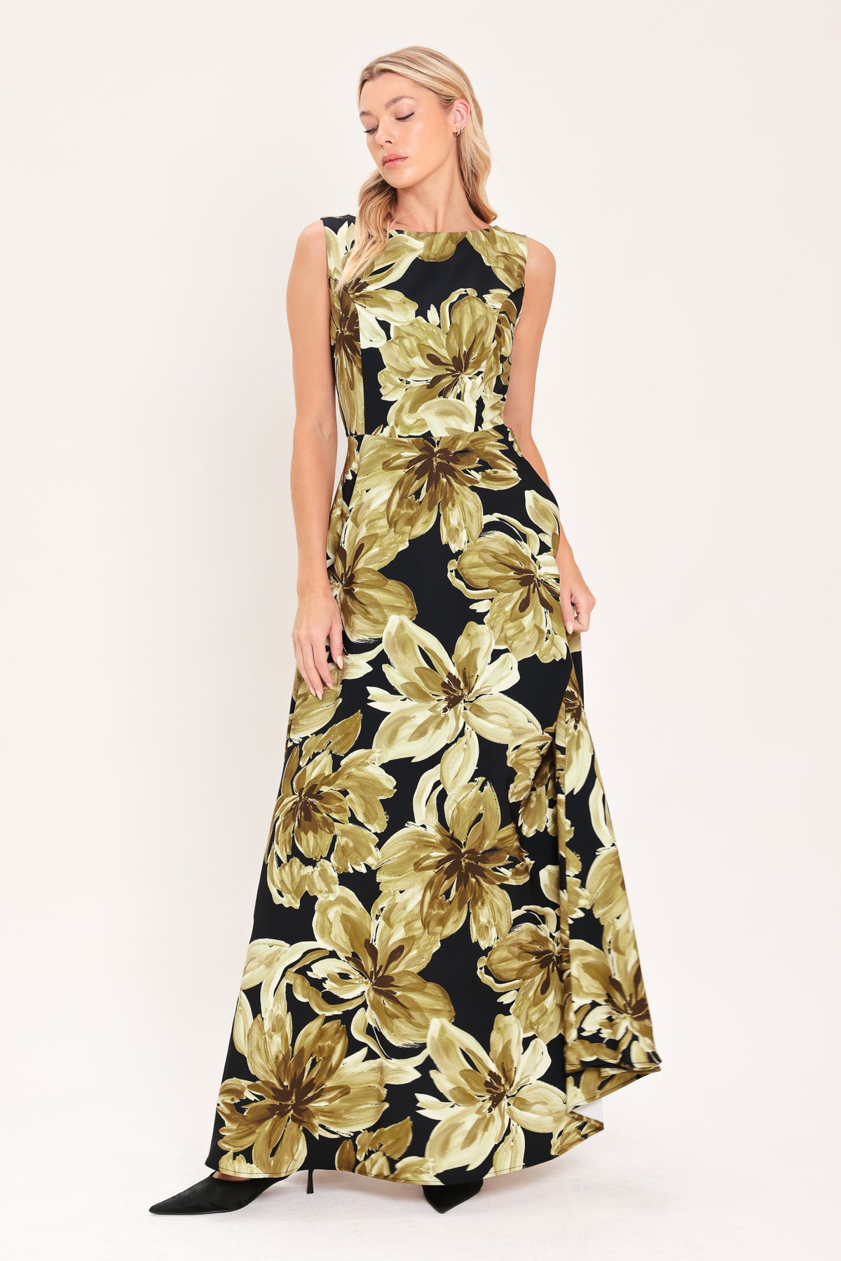 A woman modeling a sleeveless, floor-length maxi dress with a black background and a large gold floral print | Flying Tomato