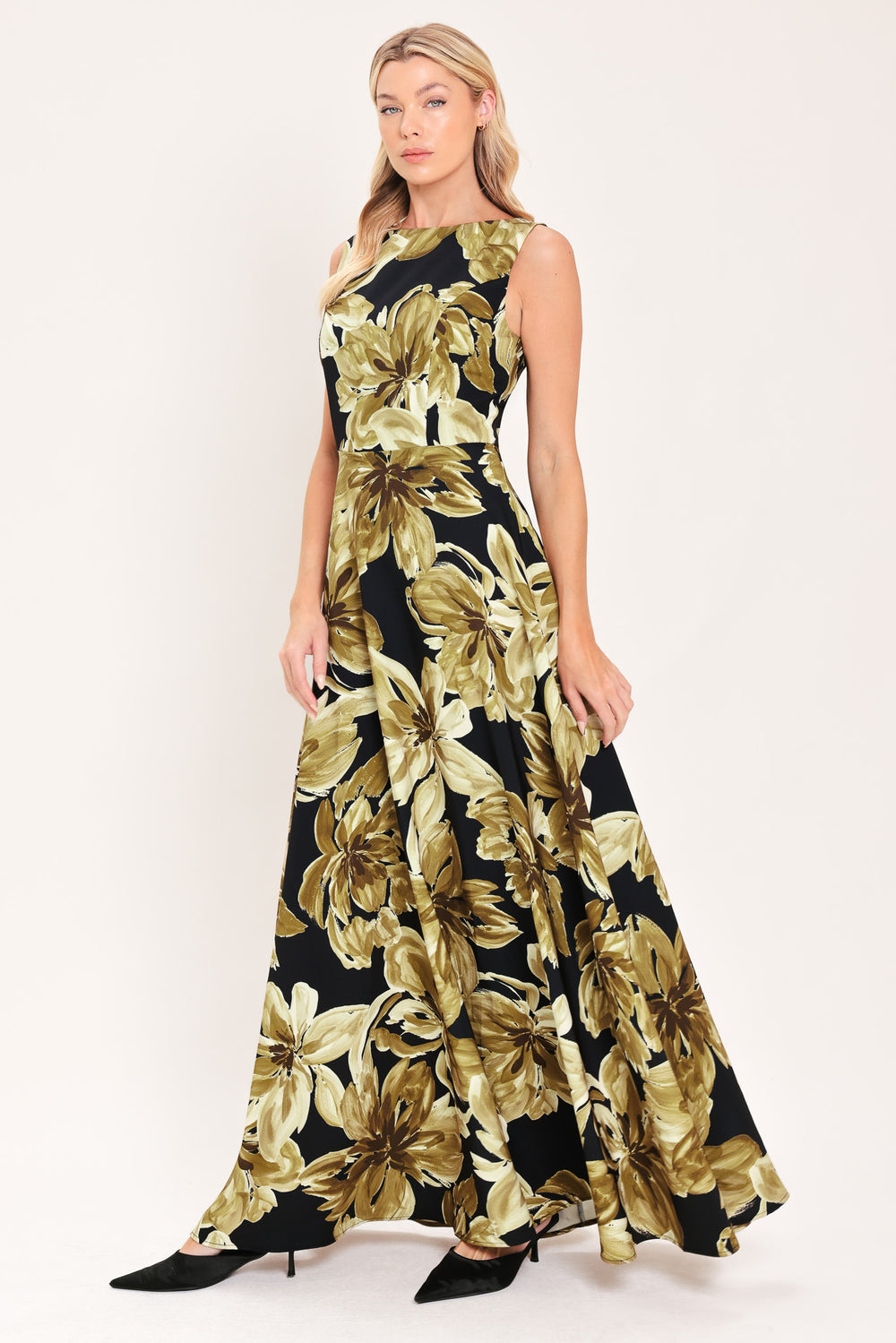 A woman modeling a sleeveless, floor-length maxi dress with a black background and a large gold floral print | Flying Tomato
