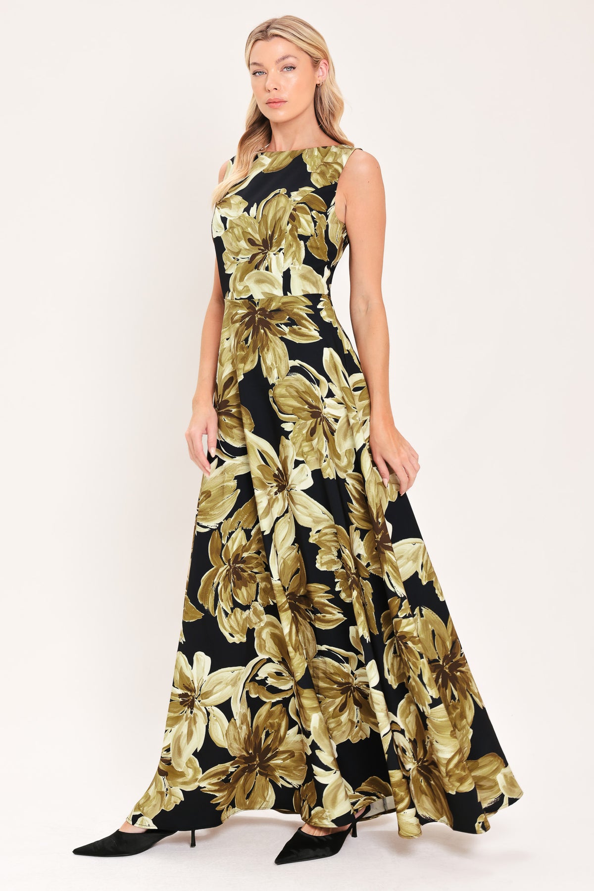 A woman modeling a sleeveless, floor-length maxi dress with a black background and a large gold floral print | Flying Tomato