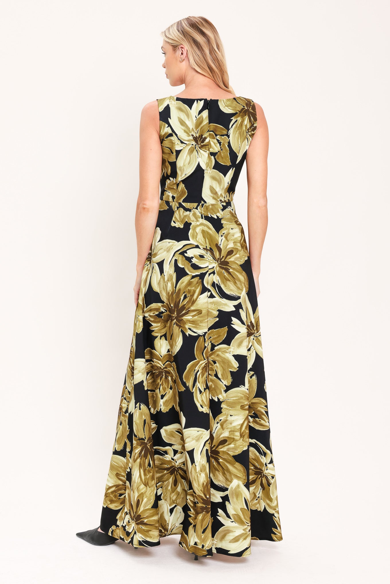 A woman modeling a sleeveless, floor-length maxi dress with a black background and a large gold floral print | Flying Tomato