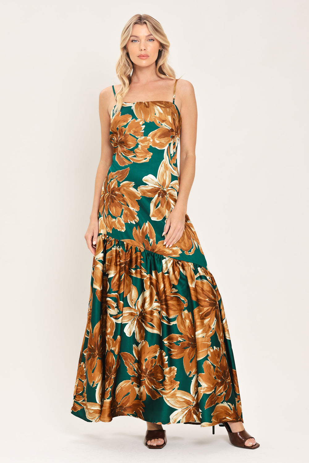 Woman wearing a spaghetti strap green maxi dress with brown floral pattern printed and asymmetrical tier from the thigh down | Flying Tomato