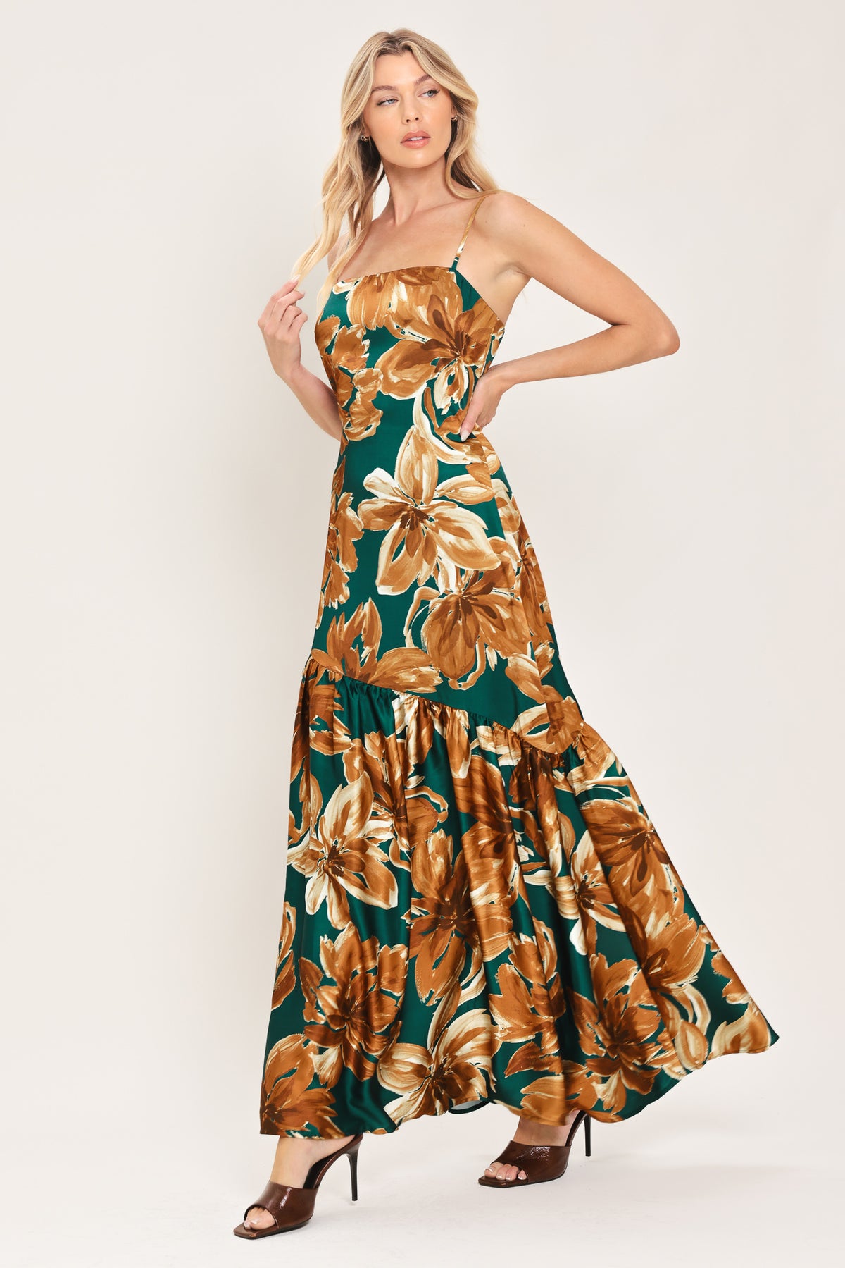 Woman wearing a spaghetti strap green maxi dress with brown floral pattern printed and asymmetrical tier from the thigh down | Flying Tomato