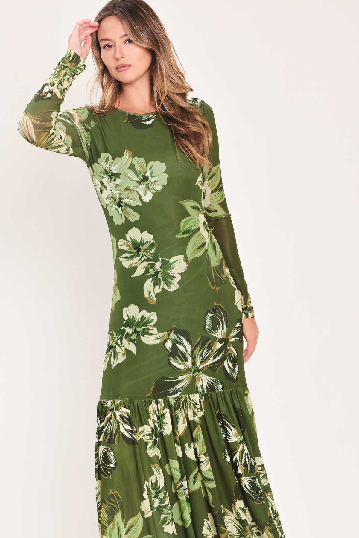 A woman modeling a long-sleeve power mesh maxi dress with a moss green and white tropical floral print | Flying Tomato