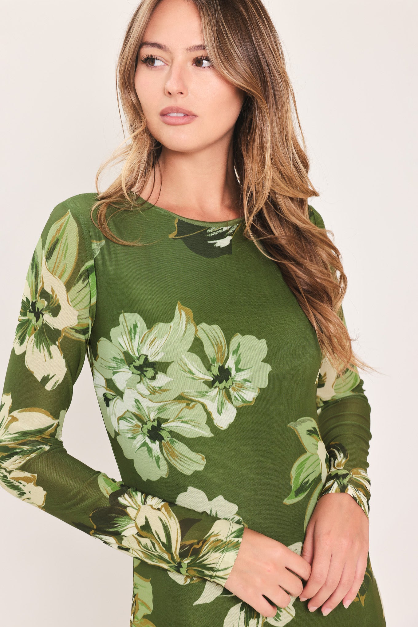A woman modeling a long-sleeve power mesh maxi dress with a moss green and white tropical floral print | Flying Tomato