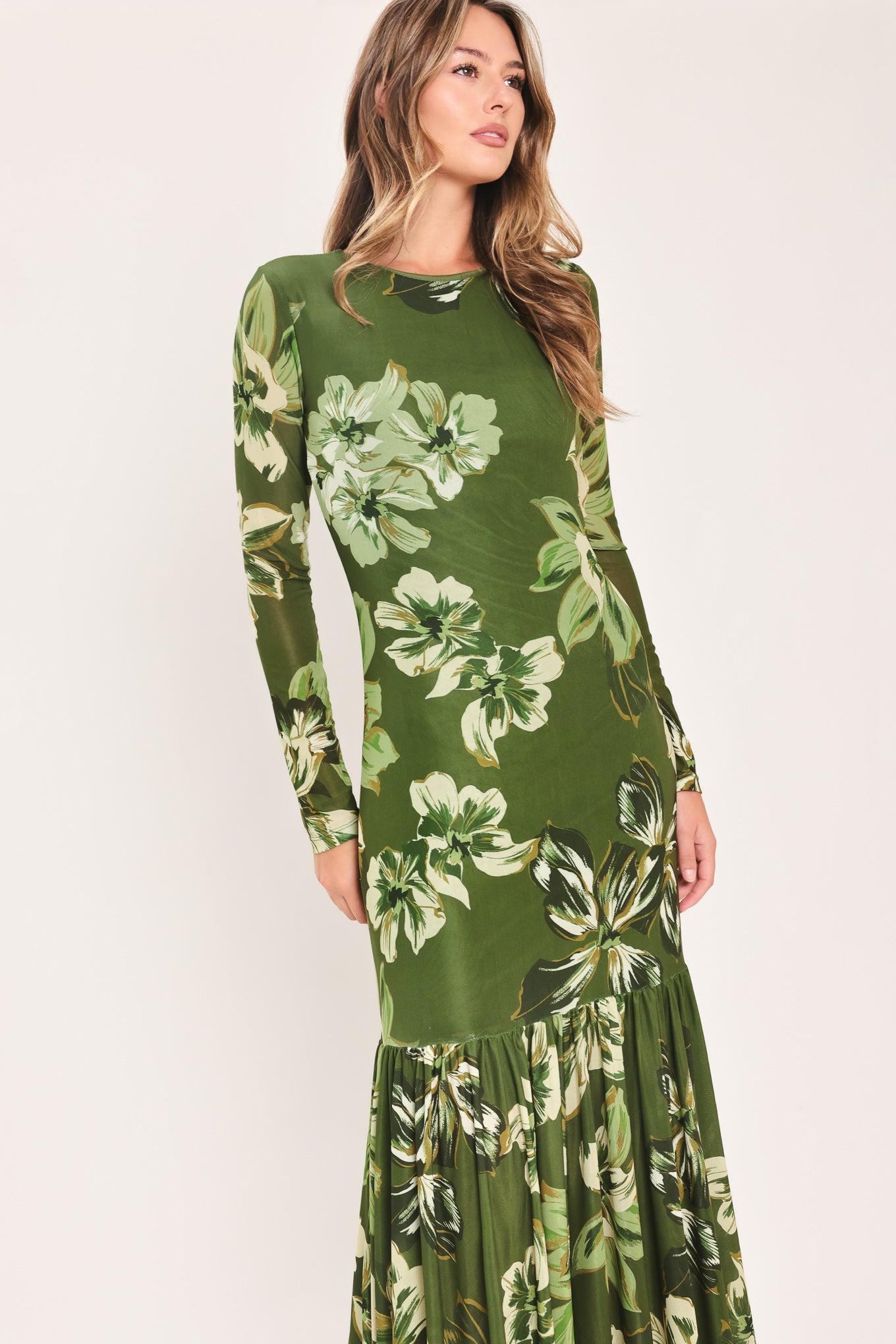 A woman modeling a long-sleeve power mesh maxi dress with a moss green and white tropical floral print | Flying Tomato