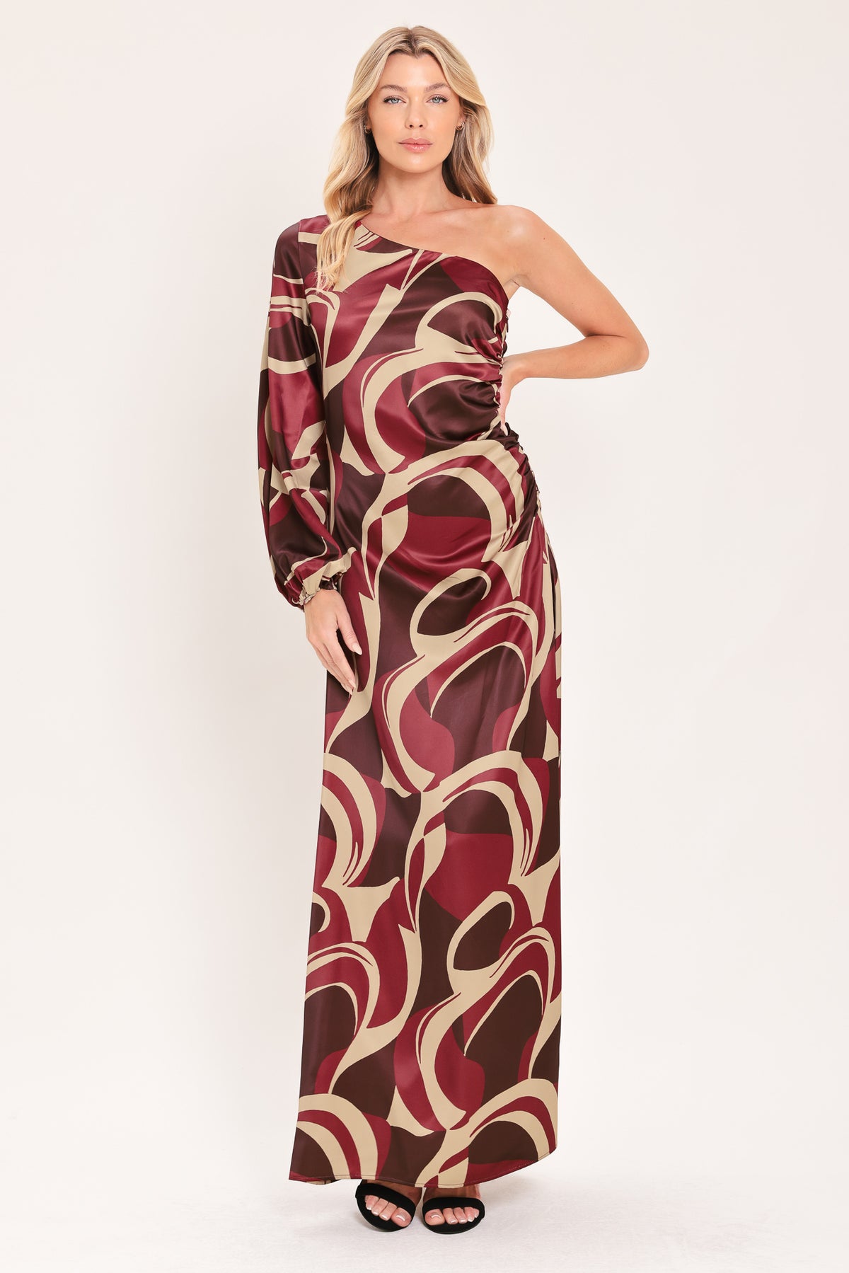 A woman modeling a one-shoulder maxi dress with a bold abstract swirl pattern in burgundy, brown, and beige | Flying Tomato
