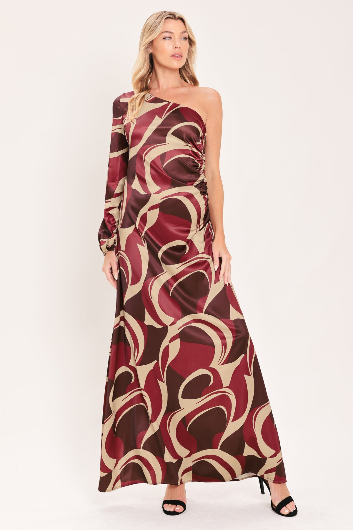 A woman modeling a one-shoulder maxi dress with a bold abstract swirl pattern in burgundy, brown, and beige | Flying Tomato
