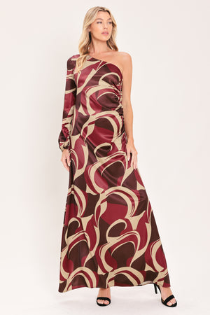 A woman modeling a one-shoulder maxi dress with a bold abstract swirl pattern in burgundy, brown, and beige | Flying Tomato
