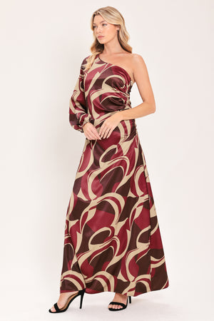 A woman modeling a one-shoulder maxi dress with a bold abstract swirl pattern in burgundy, brown, and beige | Flying Tomato