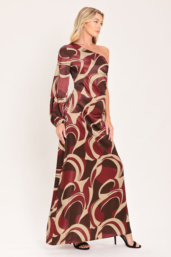 A woman modeling a one-shoulder maxi dress with a bold abstract swirl pattern in burgundy, brown, and beige | Flying Tomato