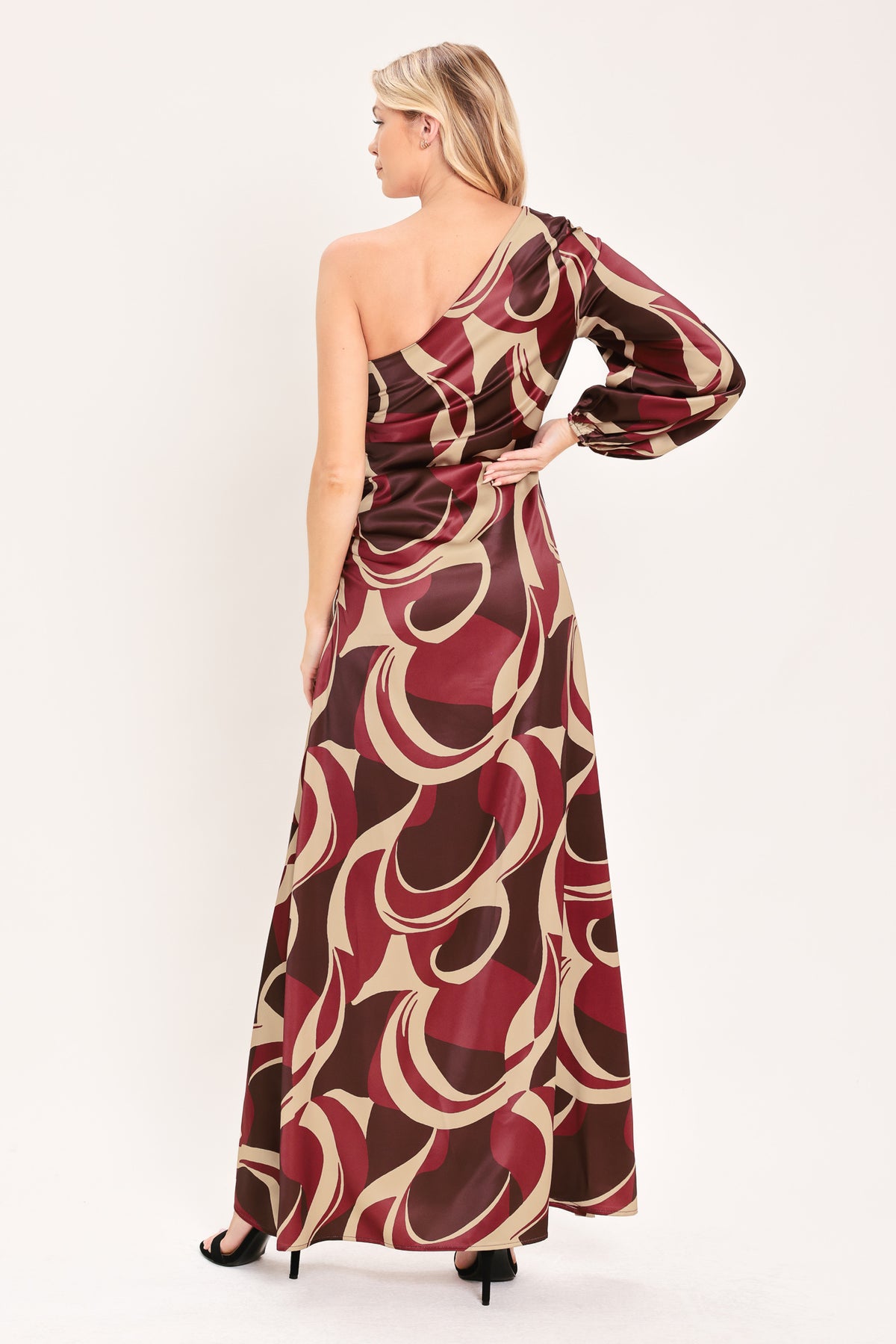 A woman modeling a one-shoulder maxi dress with a bold abstract swirl pattern in burgundy, brown, and beige | Flying Tomato