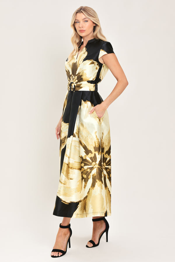 Woman wearing a black short sleeve midi dress with big gold/beige floral print, v-neck, matching waist belt, and pockets | Flying Tomato