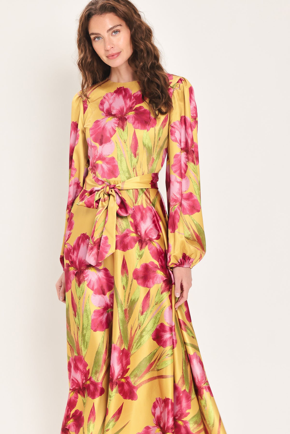 Woman wearing a long sleeve golden yellow midi dress with pink florals printed and self tie waist belt | Flying Tomato