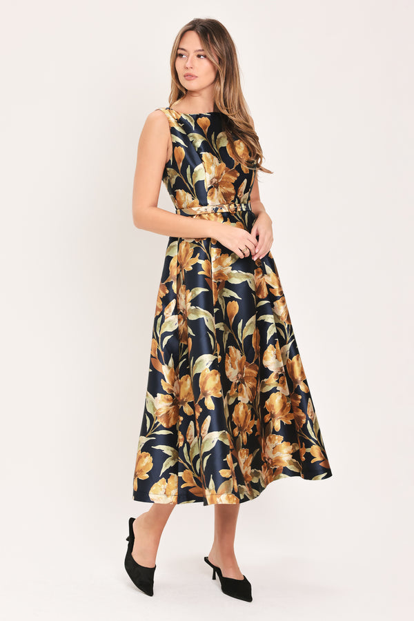 A woman modeling a sleeveless A-line midi dress with a dark navy blue background and a large yellow and gold floral print, featuring a matching fabric tie belt at the waist | Flying Tomato
