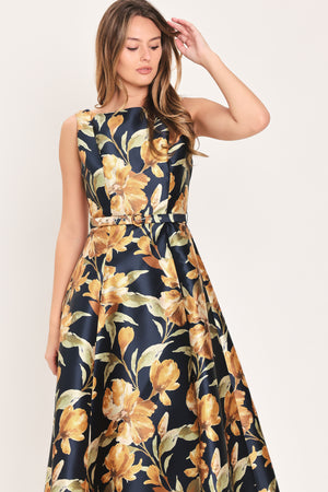 A woman modeling a sleeveless A-line midi dress with a dark navy blue background and a large yellow and gold floral print, featuring a matching fabric tie belt at the waist | Flying Tomato