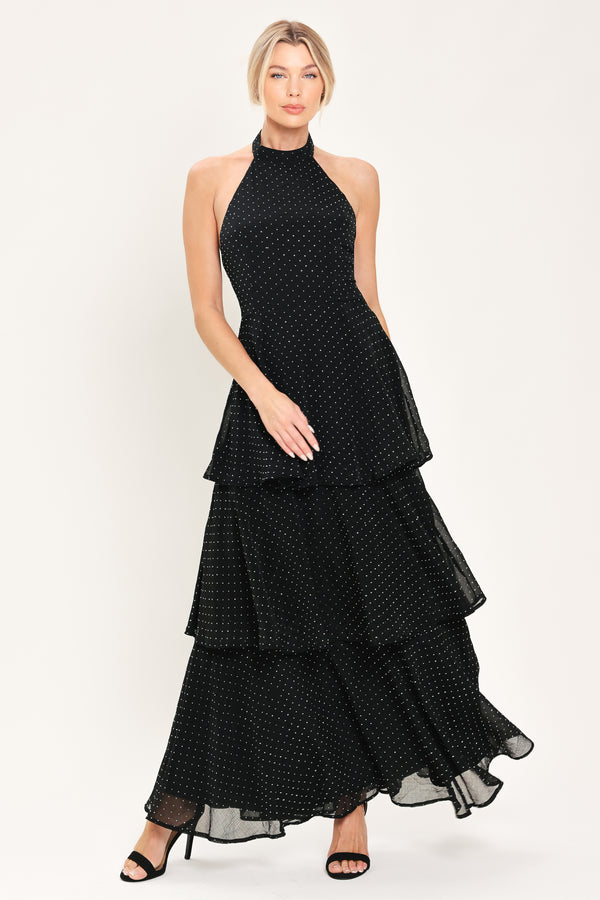 Woman wearing a sleeveless halter black maxi dress with small rhinestones and tiered skirt | Flying Tomato