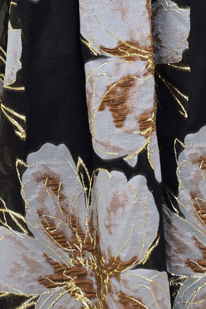 Woman wearing a strapless black maxi dress with a bluish grey floral print and gold details printed on the skirt | Flying Tomato