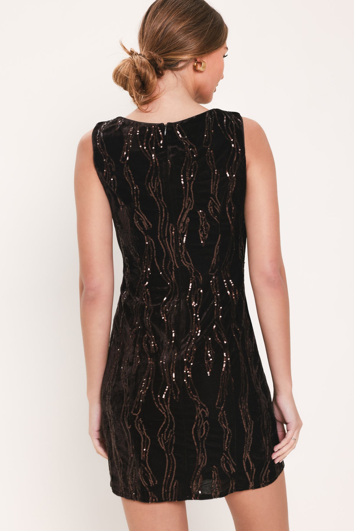 Woman wearing a sleeveless dark brown velvet mini dress with a squiggly vertical sequins line pattern | Flying Tomato