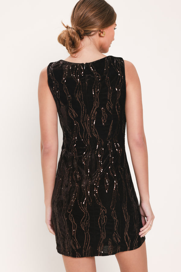 Woman wearing a sleeveless dark brown velvet mini dress with a squiggly vertical sequins line pattern | Flying Tomato
