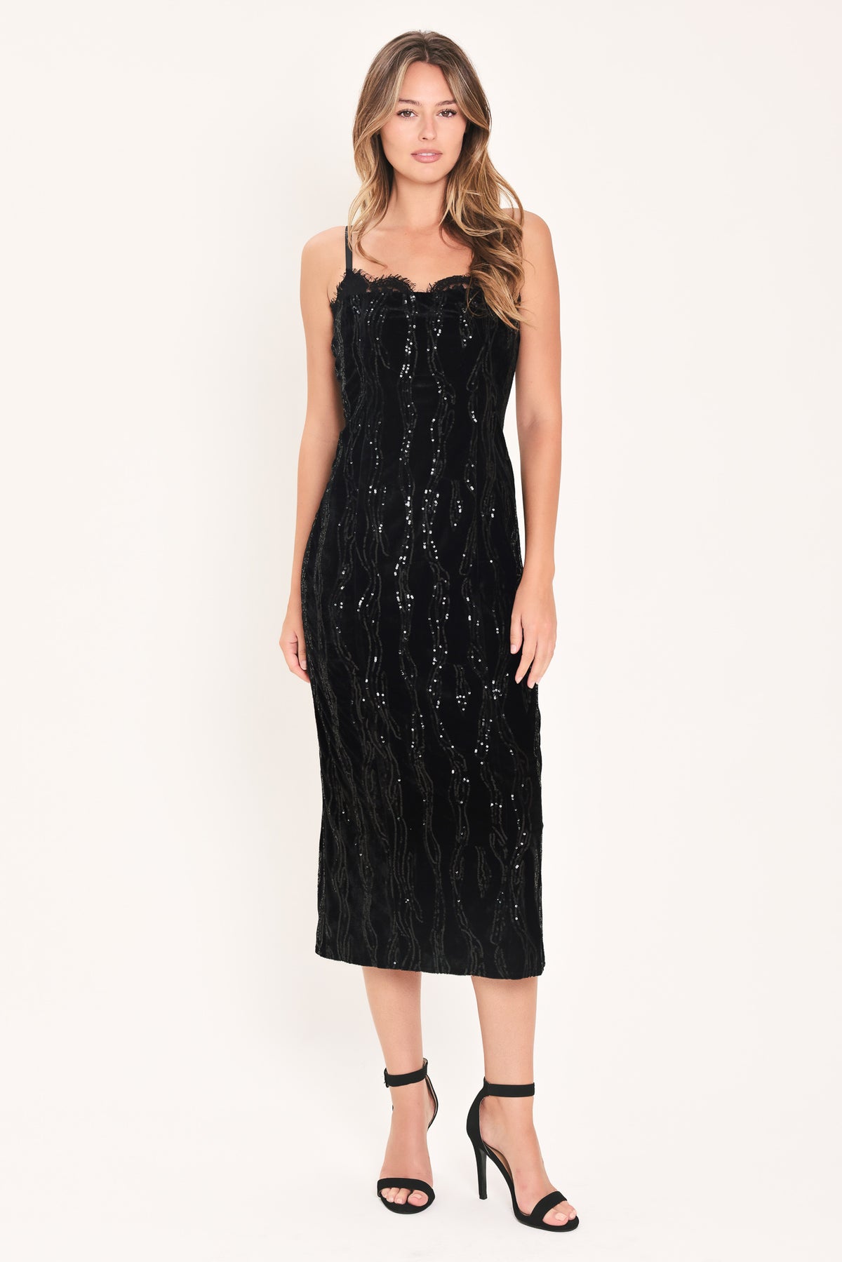A woman modeling a black sequined midi dress with spaghetti straps and a sweetheart neckline | Flying Tomato