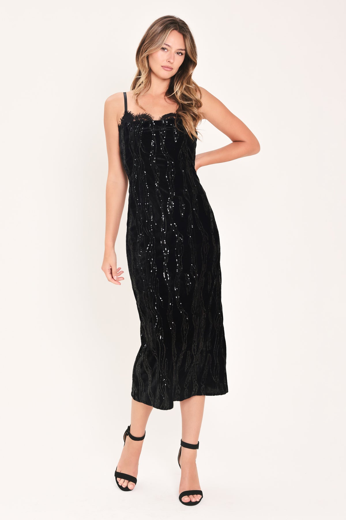 A woman modeling a black sequined midi dress with spaghetti straps and a black lace sweetheart neckline | Flying Tomato