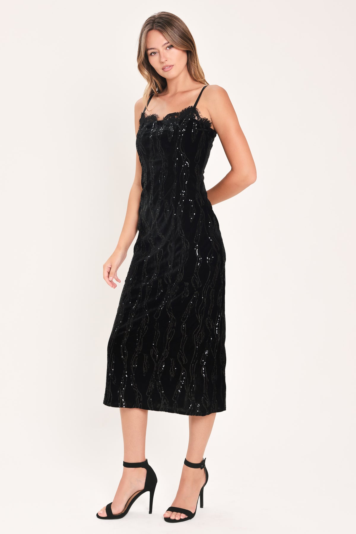 A woman modeling a black sequined midi dress with spaghetti straps and a black lace sweetheart neckline | Flying Tomato