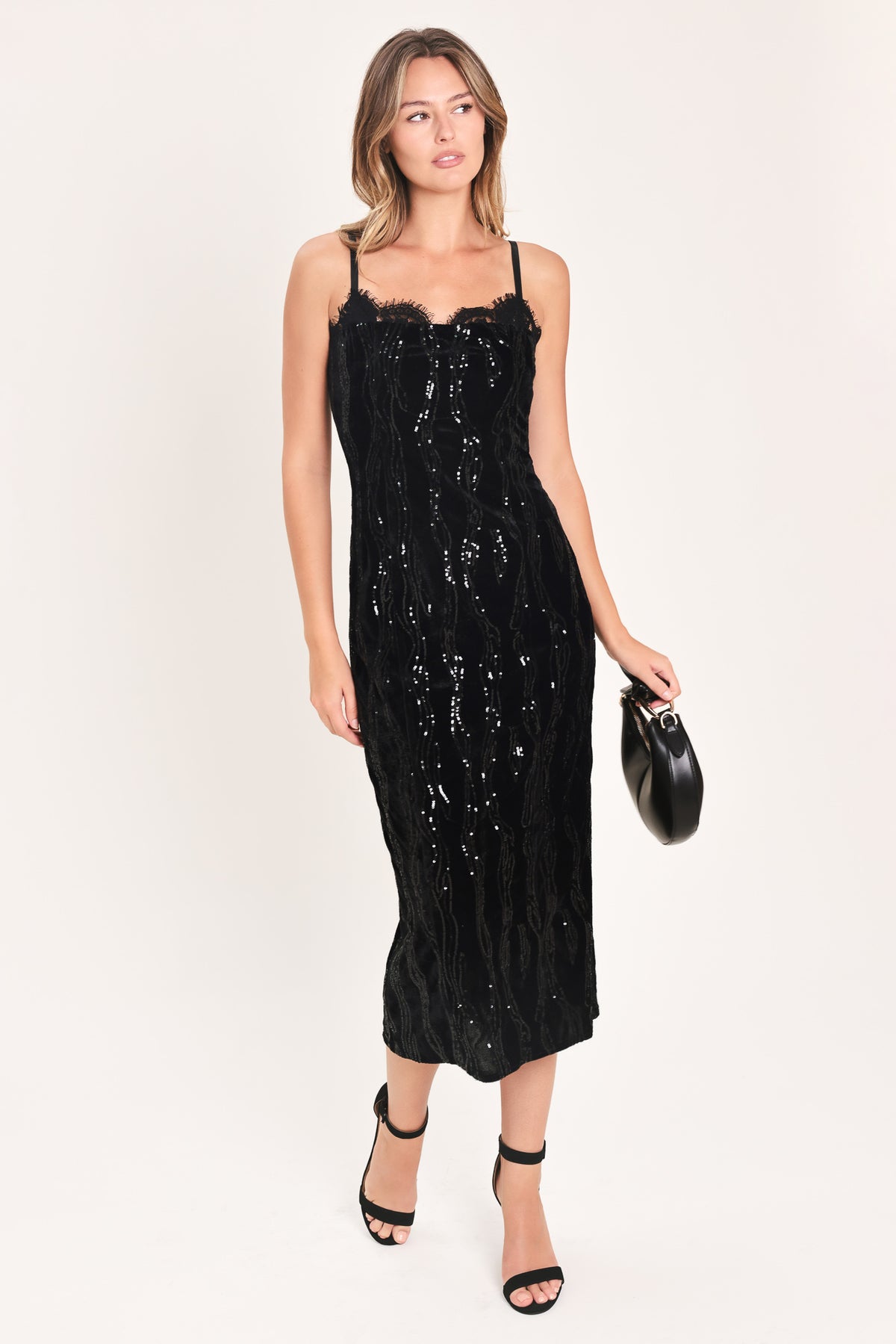 A woman modeling a black sequined midi dress with spaghetti straps and a black lace sweetheart neckline | Flying Tomato