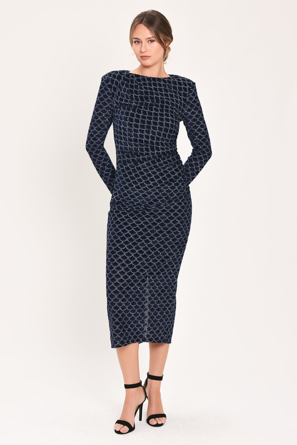 Woman wearing a long sleeve navy blue velvet midi dress with a fish scale pattern outlined with embellishments | Flying Tomato