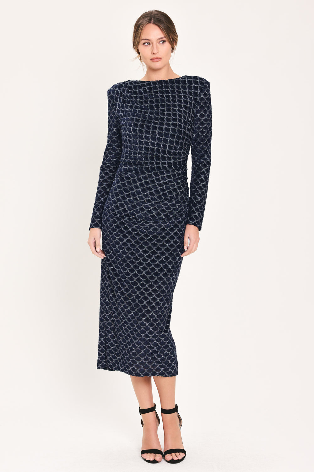 Woman wearing a long sleeve navy blue velvet midi dress with a fish scale pattern outlined with embellishments | Flying Tomato