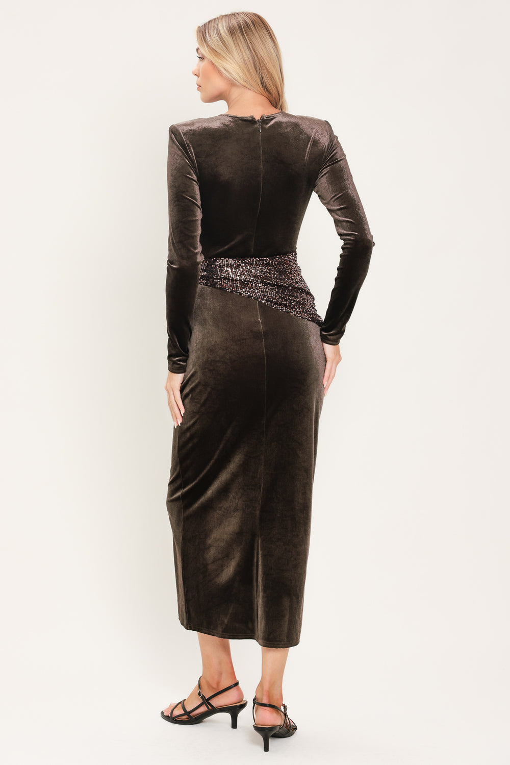 A woman modeling a long-sleeve, round-neck midi dress in dark brown velvet with a matching sequined sash belt at the waist | Flying Tomato