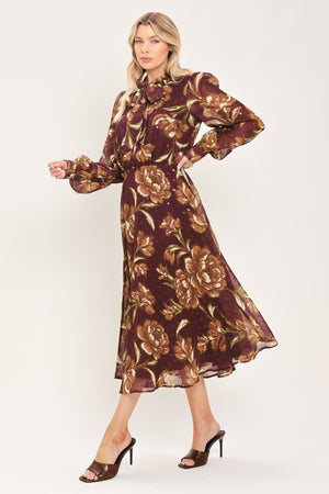 A woman modeling a long-sleeve burgundy midi dress with a brown and gold floral print, featuring a high neck, ruffled collar, and a self-tie belt at the waist | Flying Tomato