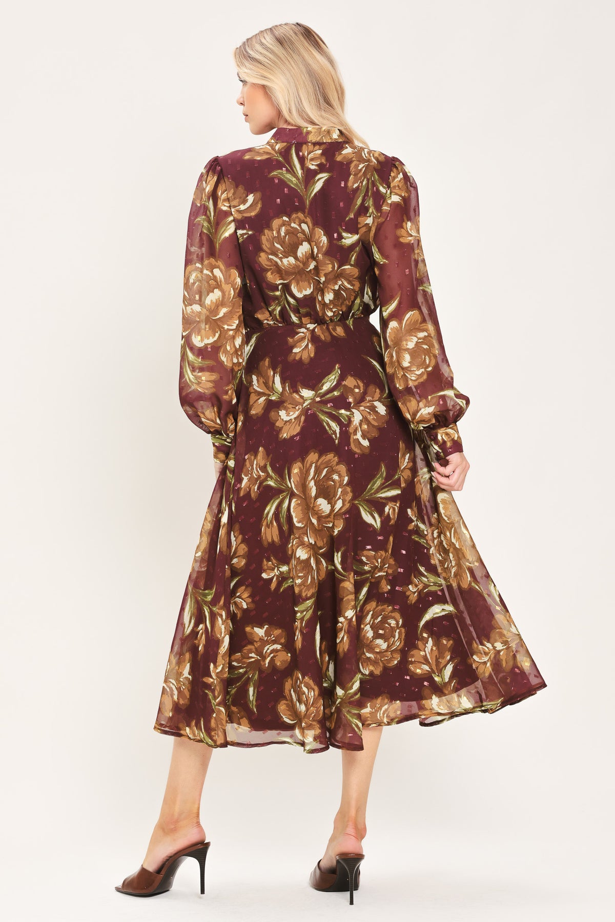 A woman modeling a long-sleeve burgundy midi dress with a brown and gold floral print, featuring a high neck, ruffled collar, and a self-tie belt at the waist | Flying Tomato