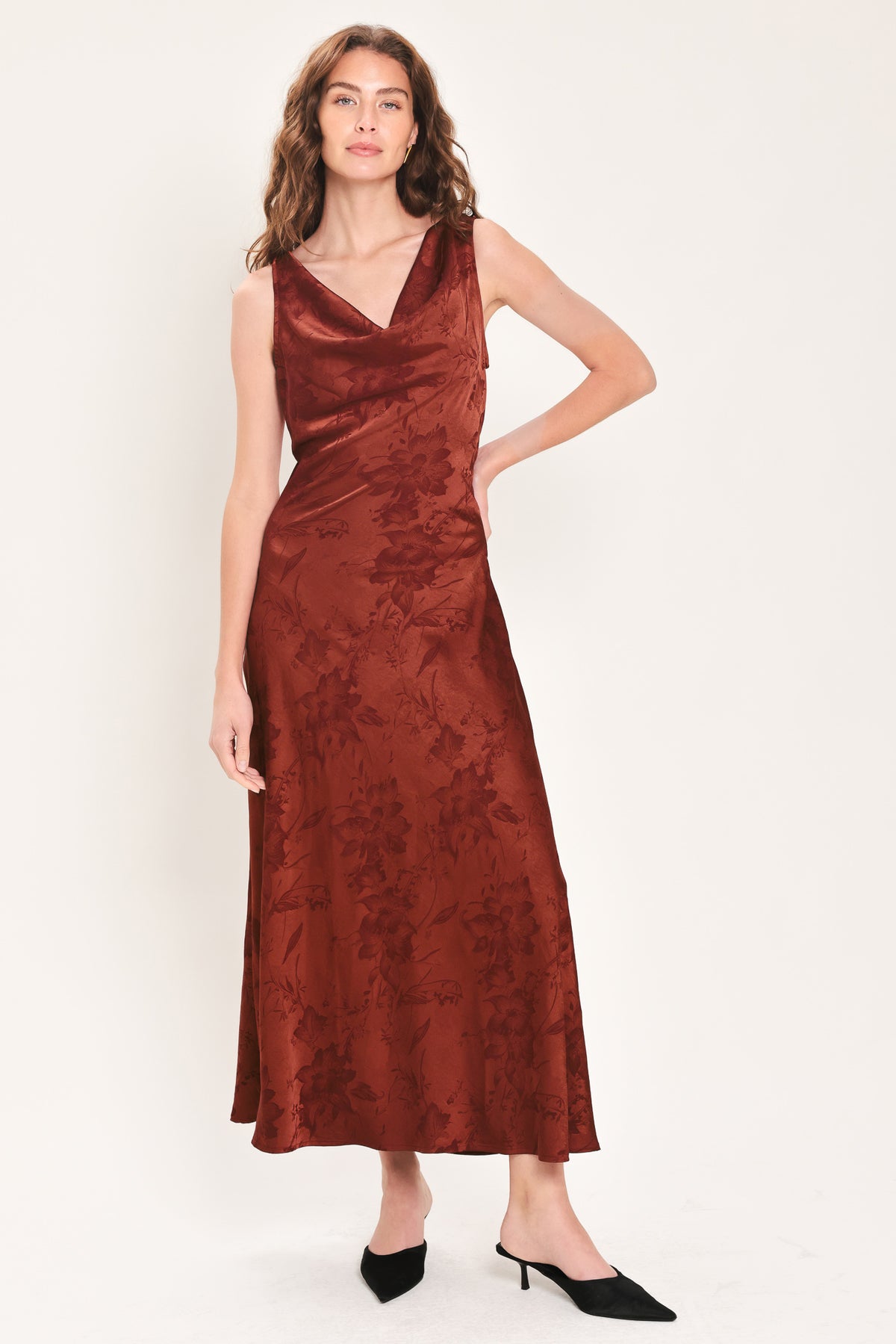 Woman wearing a sleeveless brick red satin jacquard midi dress with a cowl neckline and u-back | Flying Tomato