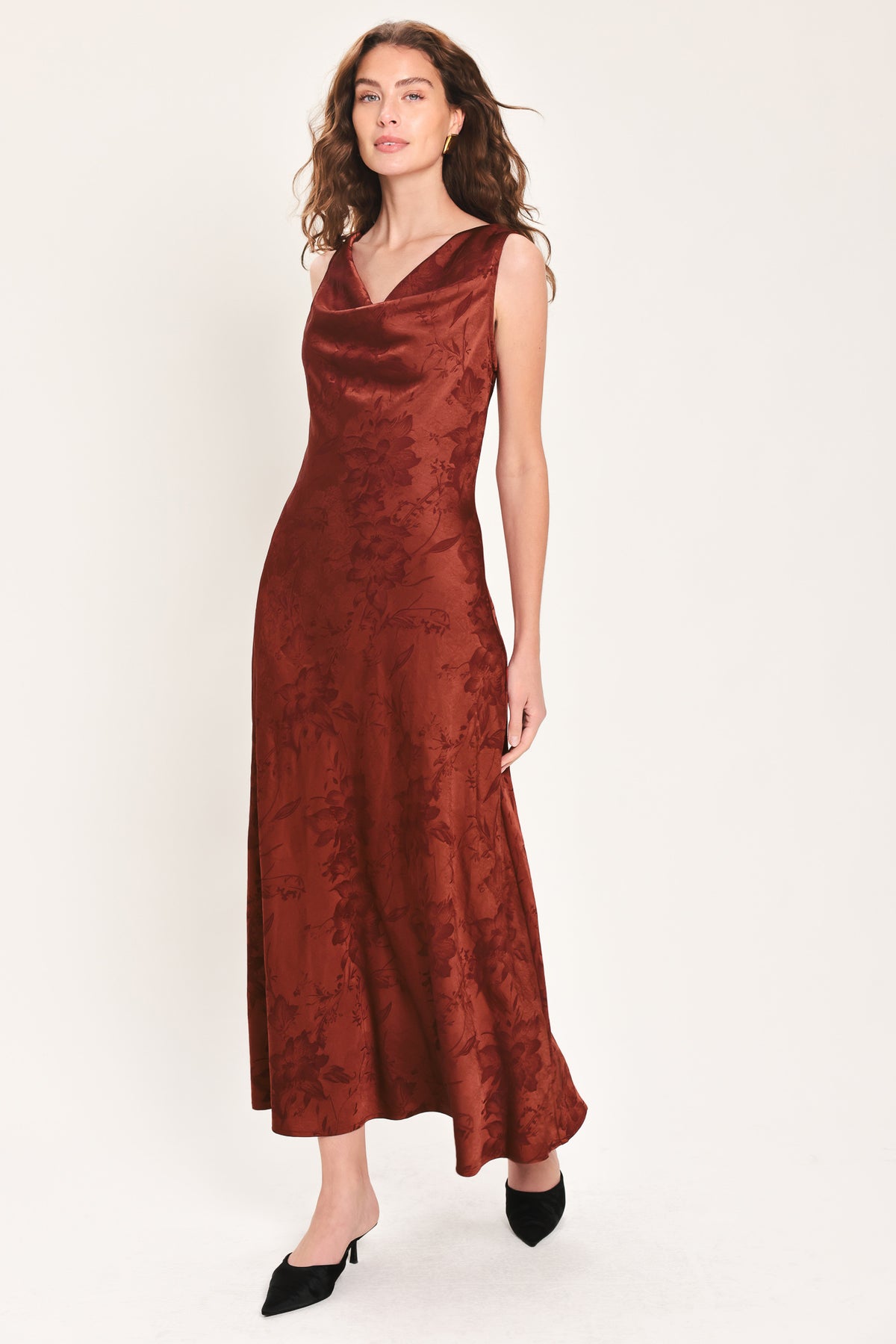 Woman wearing a sleeveless brick red satin jacquard midi dress with a cowl neckline and u-back | Flying Tomato