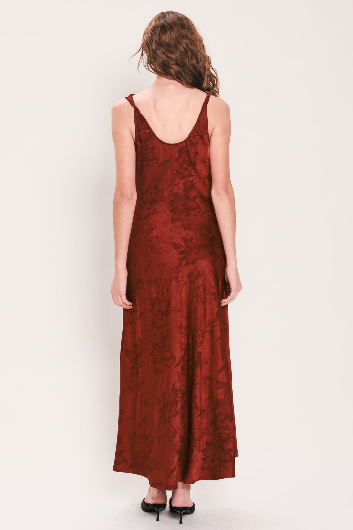 Woman wearing a sleeveless brick red satin jacquard midi dress with a cowl neckline and u-back | Flying Tomato