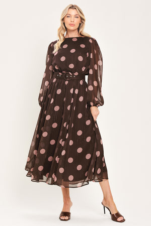 A woman modeling a brown midi dress with a pink polka dot pattern, long sheer sleeves, and a matching belt | Flying Tomato