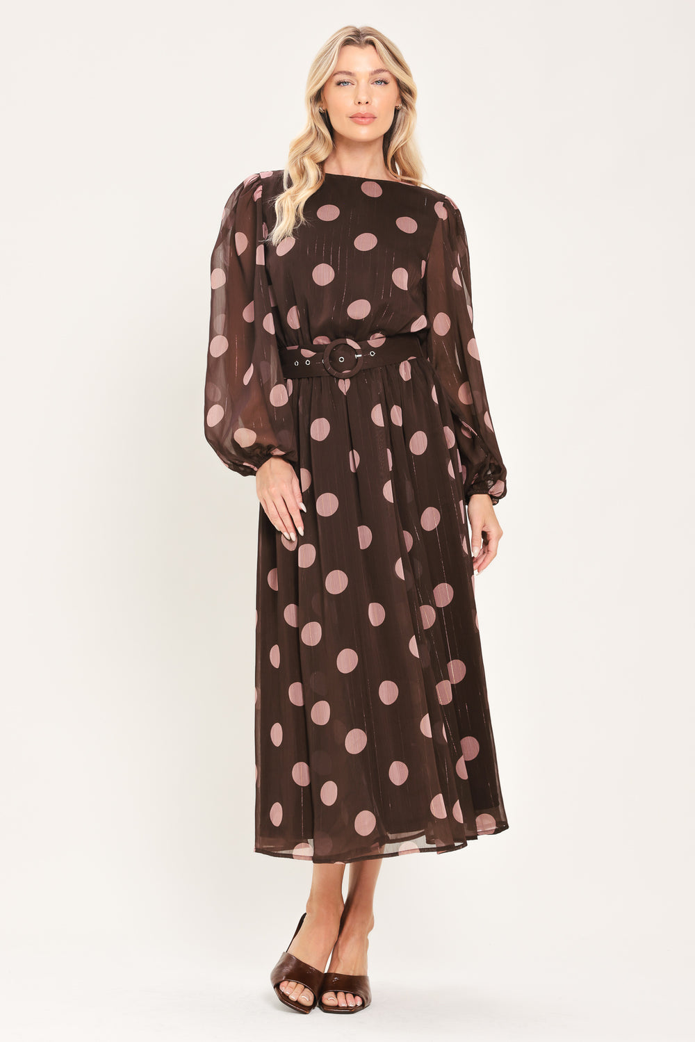 A woman modeling a brown midi dress with a pink polka dot pattern, long sheer sleeves, and a matching belt | Flying Tomato