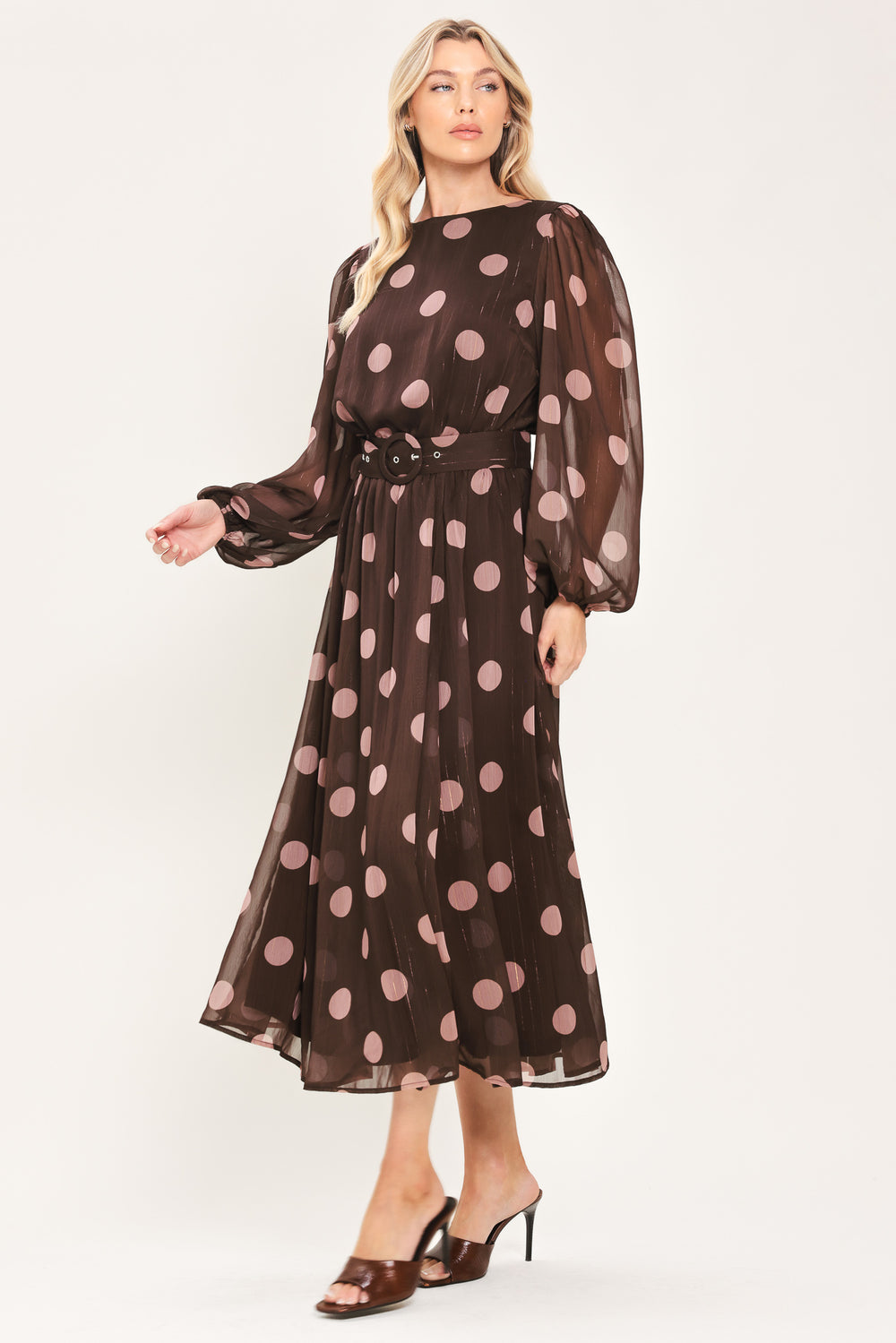 A woman modeling a brown midi dress with a pink polka dot pattern, long sheer sleeves, and a matching belt | Flying Tomato