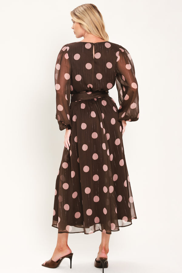 A woman modeling a brown midi dress with a pink polka dot pattern, long sheer sleeves, and a matching belt | Flying Tomato