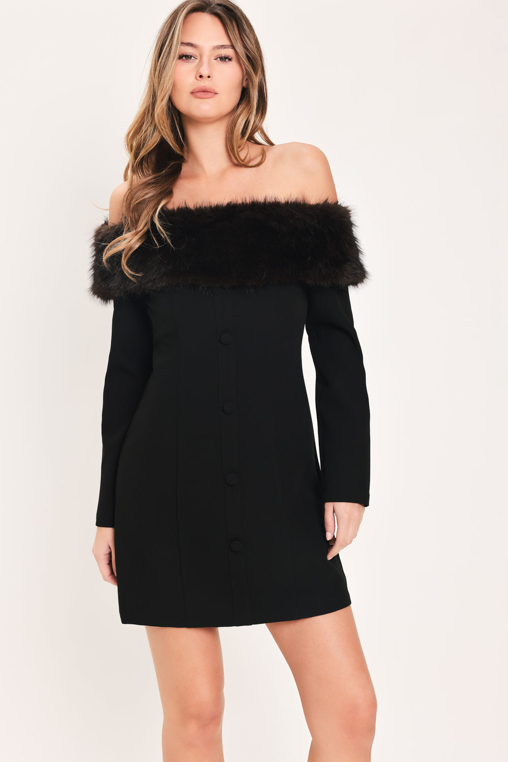 A woman modeling a black off-the-shoulder long-sleeve mini dress with a wide black faux-fur collar and a front button closure | Flying Tomato