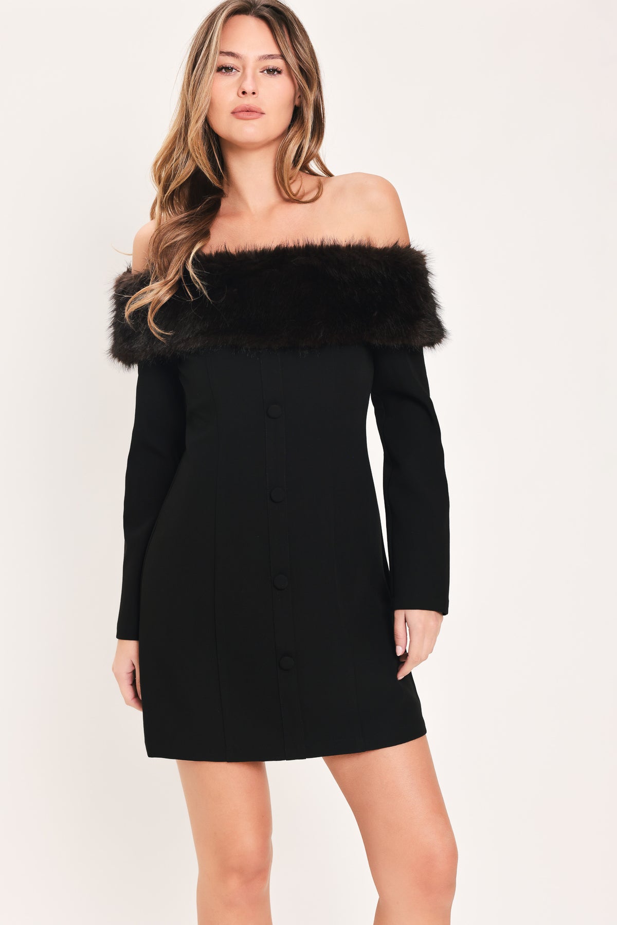 A woman modeling a black off-the-shoulder long-sleeve mini dress with a wide black faux-fur collar and a front button closure | Flying Tomato