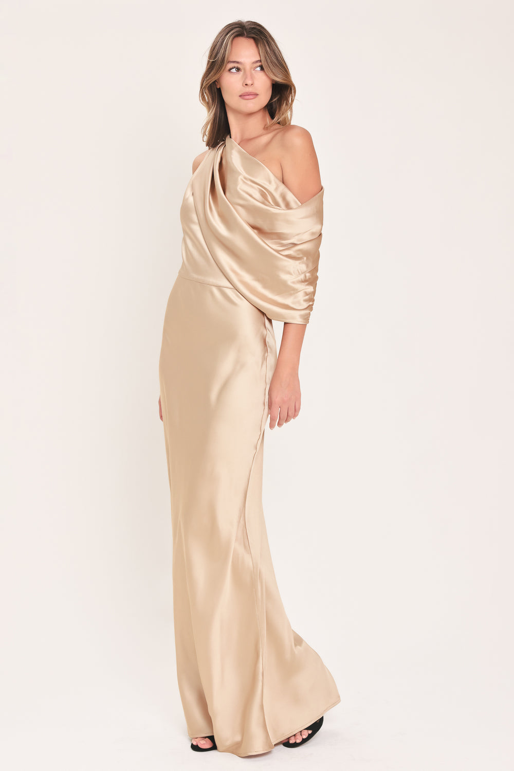A woman modeling a floor-length maxi draped satin gown in deep burgundy wine, featuring an asymmetrical draped neckline and one sleeve | Flying Tomato