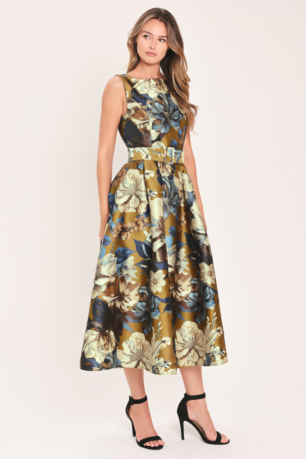 A woman modeling a sleeveless midi dress with a floral print in olive green, navy blue, beige, and white | Flying Tomato